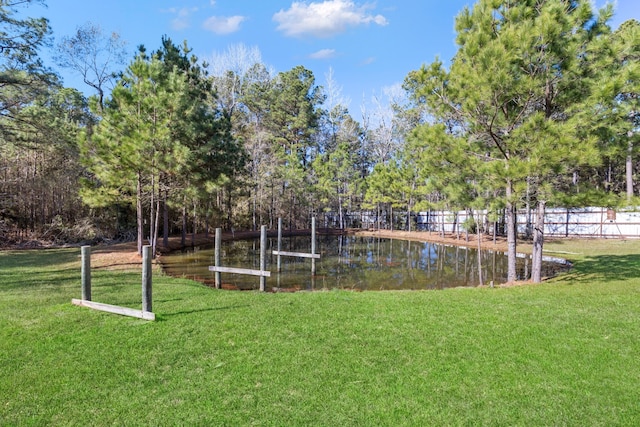 surrounding community with a water view and a yard