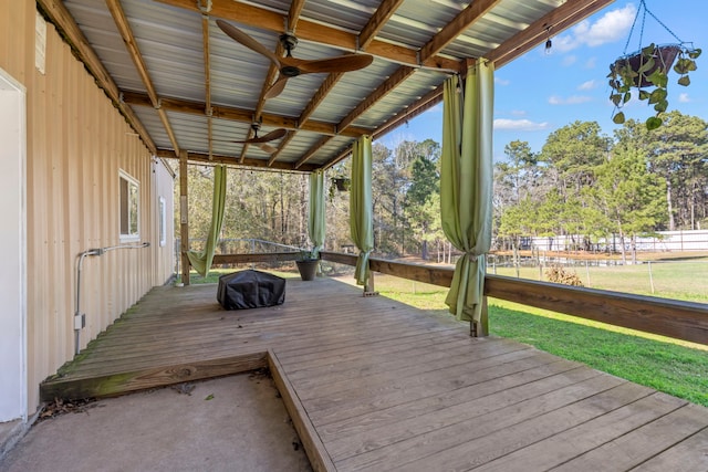 wooden terrace featuring ceiling fan and a lawn