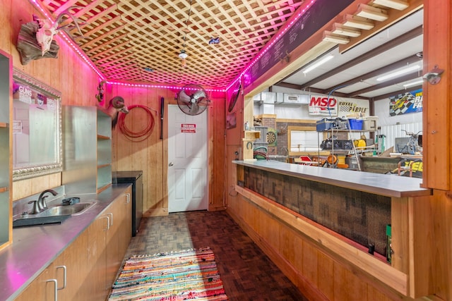 bar with sink, stainless steel counters, and wood walls