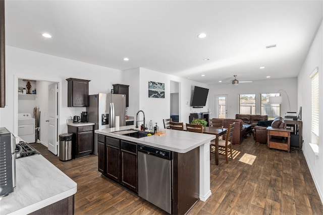 kitchen with dark hardwood / wood-style floors, ceiling fan, an island with sink, appliances with stainless steel finishes, and washer / clothes dryer