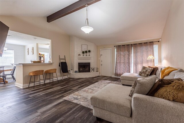 living room featuring vaulted ceiling with beams, dark wood-type flooring, and a brick fireplace