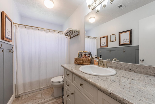 full bathroom featuring vanity, shower / bath combo, toilet, and a textured ceiling