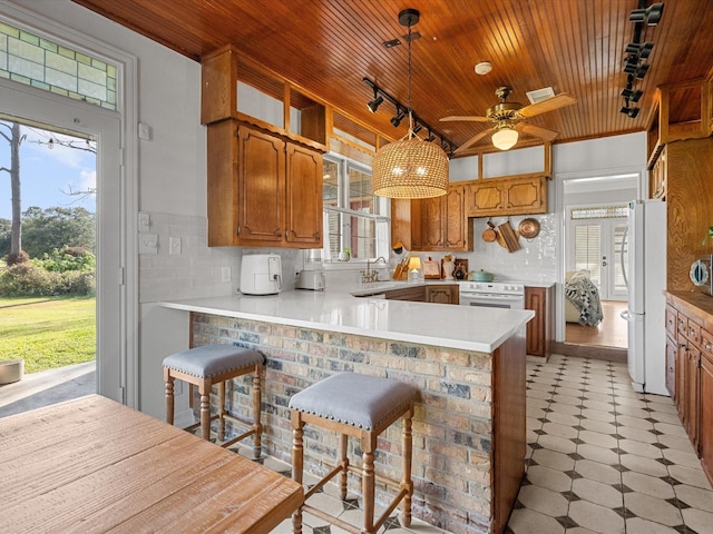 kitchen with a kitchen bar, wooden ceiling, white fridge, decorative light fixtures, and kitchen peninsula