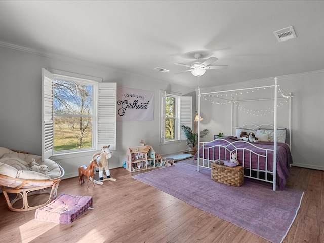 bedroom with ceiling fan, ornamental molding, multiple windows, and wood-type flooring