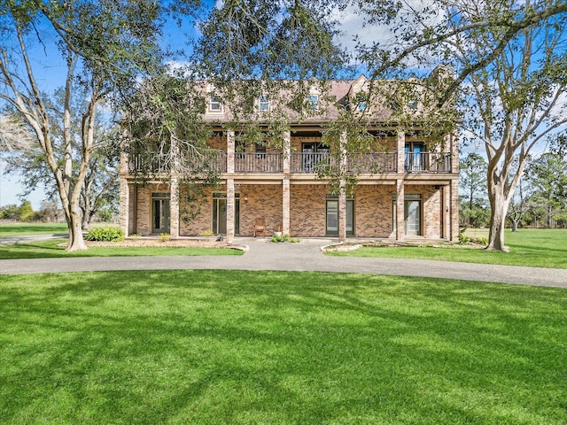 view of front of house featuring a front lawn and a balcony