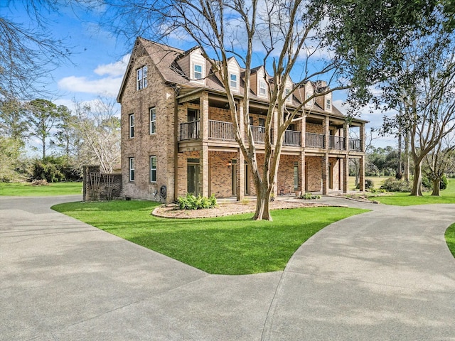 view of front of house with a balcony and a front lawn