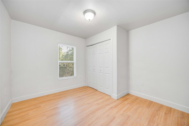 unfurnished bedroom with light wood-type flooring and a closet