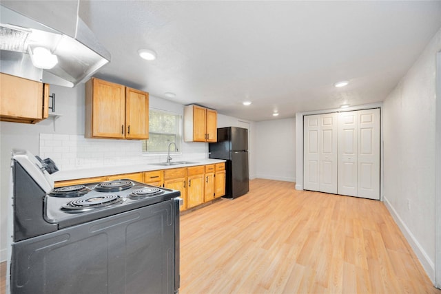 kitchen with black fridge, sink, light hardwood / wood-style flooring, range with electric stovetop, and tasteful backsplash