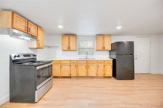 kitchen featuring stainless steel range with electric stovetop, black fridge, sink, light wood-type flooring, and light brown cabinetry