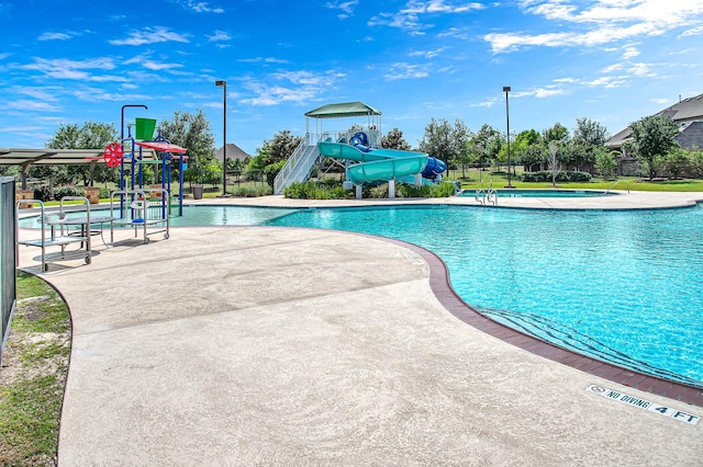 view of swimming pool featuring a playground and a water slide