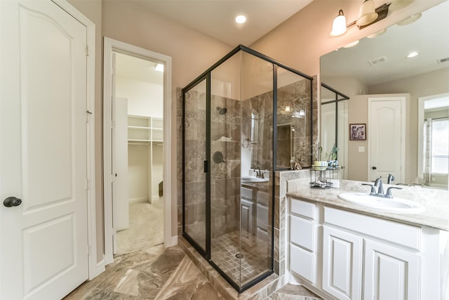 bathroom featuring a shower with door and vanity