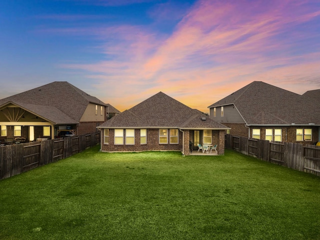 back house at dusk with a patio area and a yard