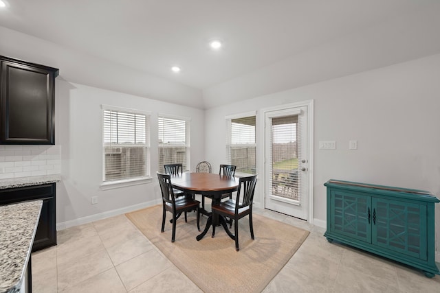 dining space with light tile patterned floors and vaulted ceiling