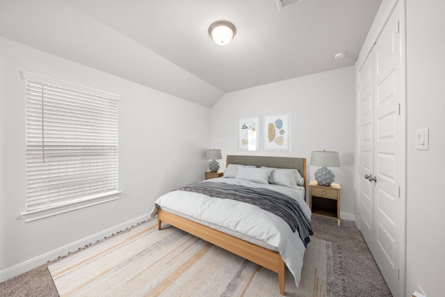 bedroom with vaulted ceiling, carpet floors, and a closet