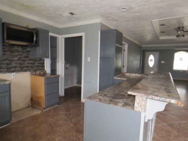 kitchen with stone counters, dark tile patterned floors, a textured ceiling, gray cabinets, and ornamental molding