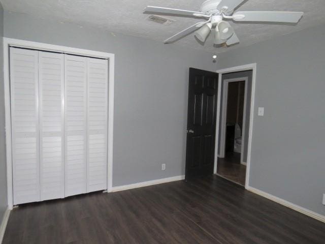 unfurnished bedroom featuring ceiling fan, dark hardwood / wood-style flooring, a textured ceiling, and a closet