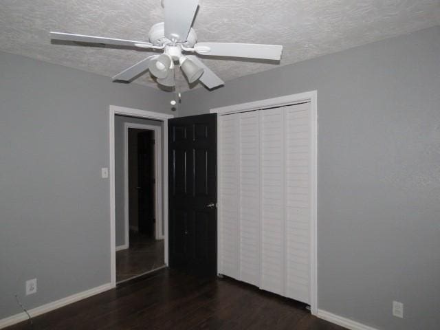 unfurnished bedroom with a textured ceiling, a closet, ceiling fan, and dark wood-type flooring