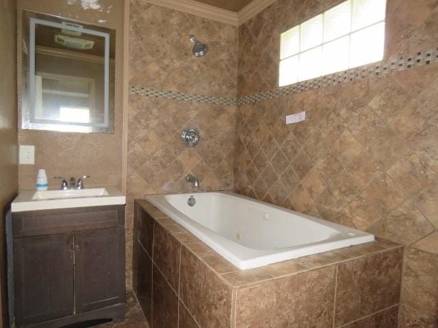 bathroom with a relaxing tiled tub, ornamental molding, tile walls, and vanity