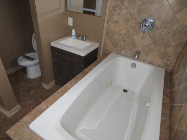 bathroom with a tub to relax in, vanity, and toilet