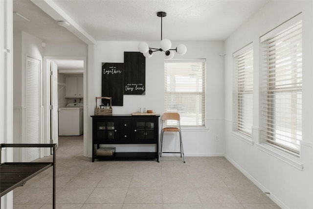 tiled dining area with a chandelier, a textured ceiling, and washer / clothes dryer