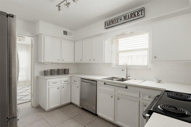 kitchen with white cabinets, light tile patterned floors, stainless steel appliances, and sink