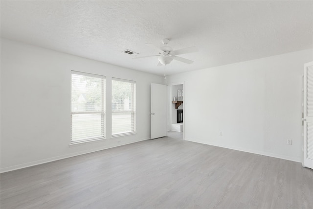 empty room featuring ceiling fan, light hardwood / wood-style flooring, and a textured ceiling