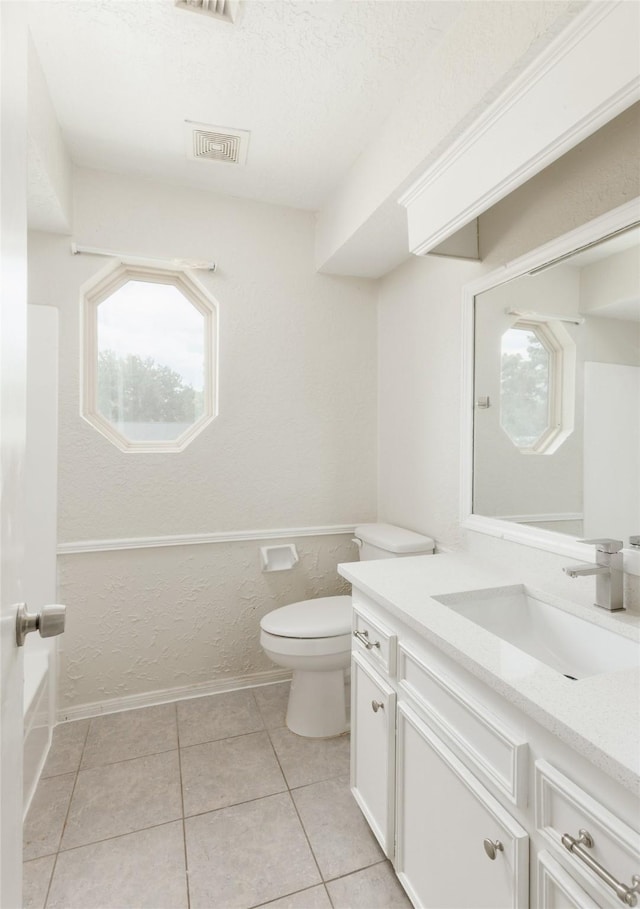 bathroom featuring tile patterned flooring, a textured ceiling, vanity, and toilet