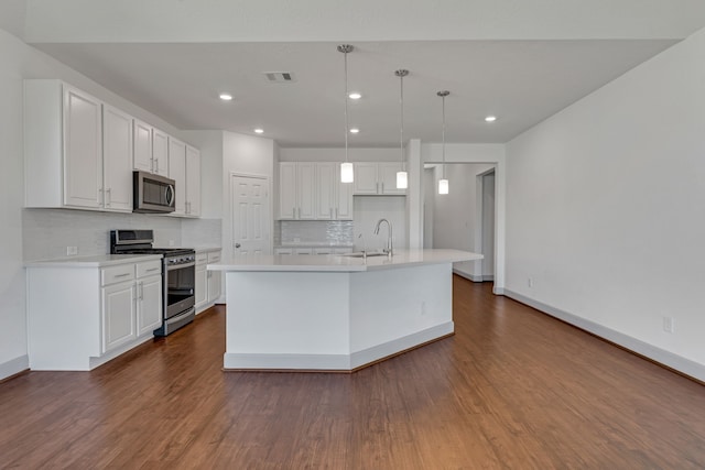 kitchen featuring backsplash, stainless steel appliances, white cabinetry, and an island with sink