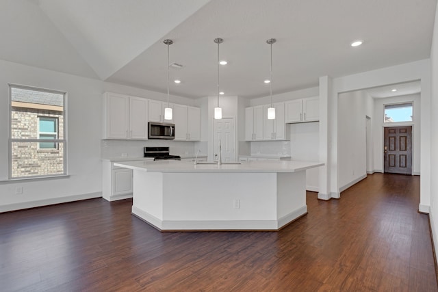 kitchen with white cabinets, hanging light fixtures, and an island with sink