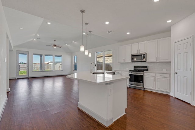 kitchen featuring appliances with stainless steel finishes, backsplash, vaulted ceiling, a center island with sink, and white cabinets