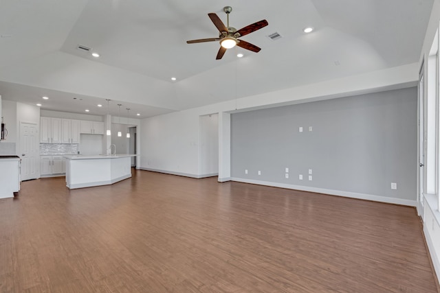 unfurnished living room with wood-type flooring, high vaulted ceiling, ceiling fan, and sink