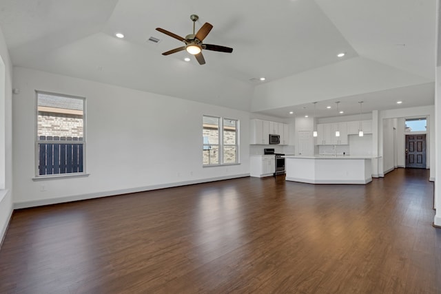 unfurnished living room with dark wood-type flooring, a tray ceiling, and lofted ceiling