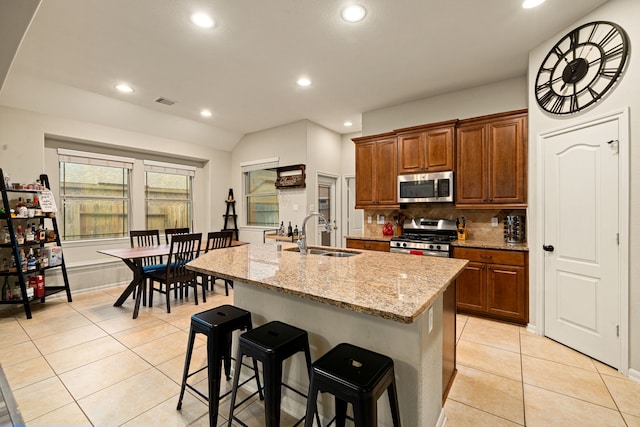 kitchen with a breakfast bar, appliances with stainless steel finishes, an island with sink, and sink