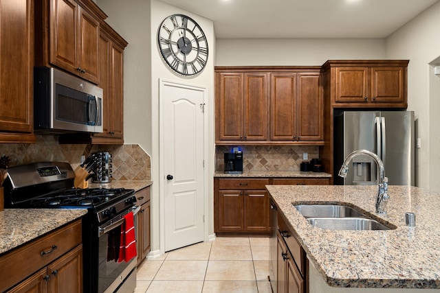 kitchen with backsplash, sink, light tile patterned floors, light stone counters, and stainless steel appliances