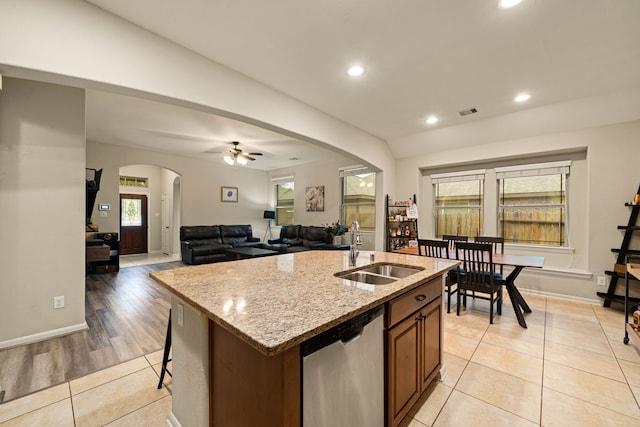 kitchen featuring stainless steel dishwasher, ceiling fan, sink, an island with sink, and light tile patterned flooring