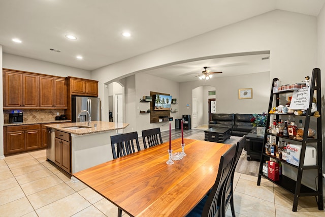 dining area with ceiling fan, sink, light tile patterned floors, and lofted ceiling