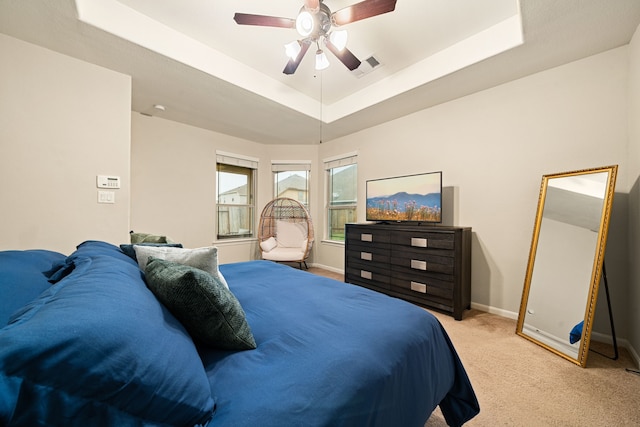 carpeted bedroom with a tray ceiling and ceiling fan