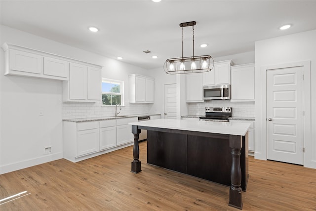 kitchen with sink, stainless steel appliances, white cabinetry, and a kitchen island