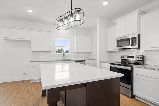 kitchen featuring white cabinets, light wood-type flooring, appliances with stainless steel finishes, and a center island