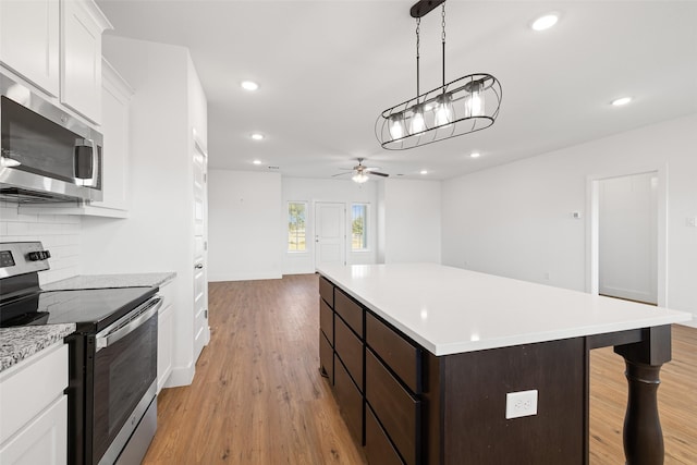 kitchen with a center island, stainless steel appliances, tasteful backsplash, ceiling fan, and dark brown cabinetry