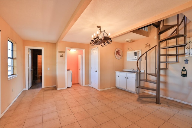 interior space featuring washer / clothes dryer, an AC wall unit, a notable chandelier, sink, and light tile patterned flooring