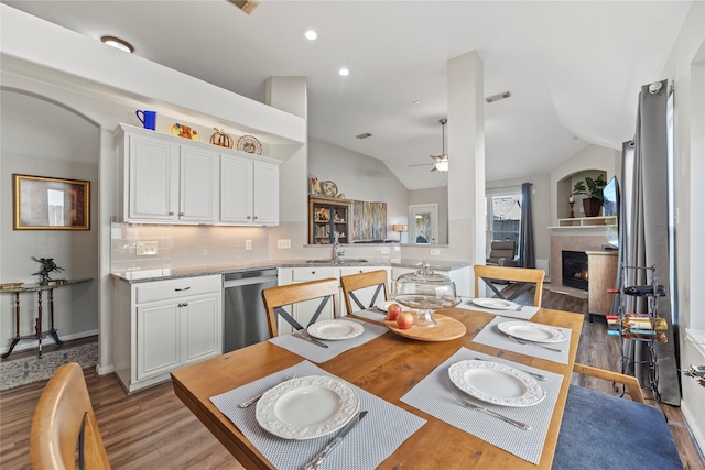 dining space featuring ceiling fan, light wood-type flooring, sink, and vaulted ceiling