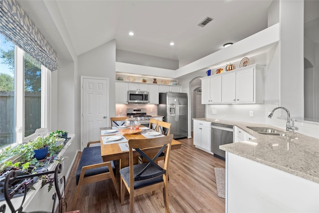 kitchen with sink, white cabinets, high vaulted ceiling, and appliances with stainless steel finishes