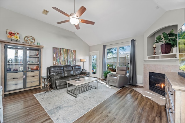 living room featuring a fireplace, vaulted ceiling, ceiling fan, and dark wood-type flooring