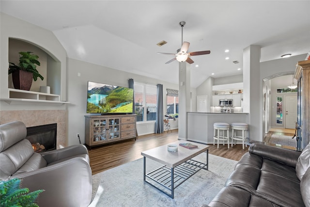 living room featuring a tiled fireplace, ceiling fan, lofted ceiling, and hardwood / wood-style flooring