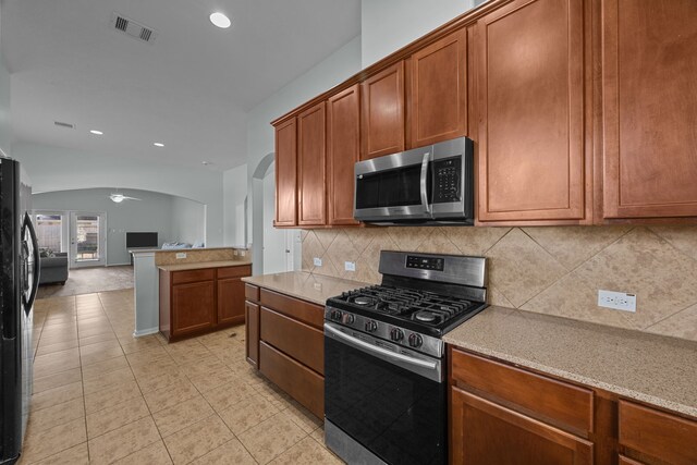 kitchen featuring light stone countertops, appliances with stainless steel finishes, tasteful backsplash, ceiling fan, and light tile patterned flooring