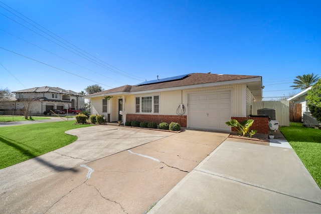 ranch-style home featuring solar panels, a garage, and a front lawn