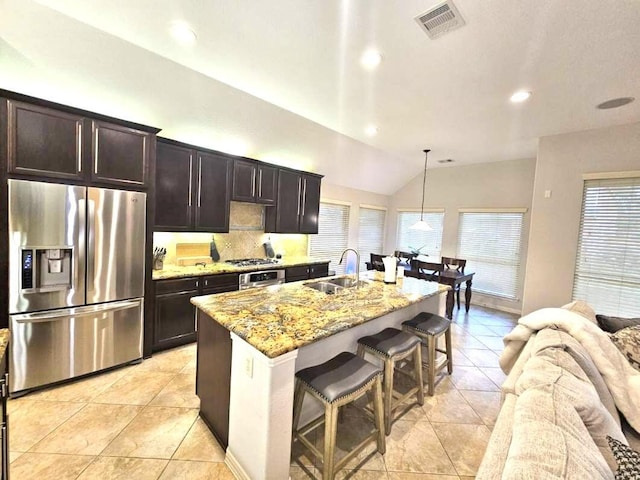 kitchen featuring stainless steel appliances, sink, a center island with sink, hanging light fixtures, and lofted ceiling