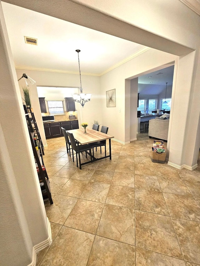 dining area with a wealth of natural light, a notable chandelier, and ornamental molding