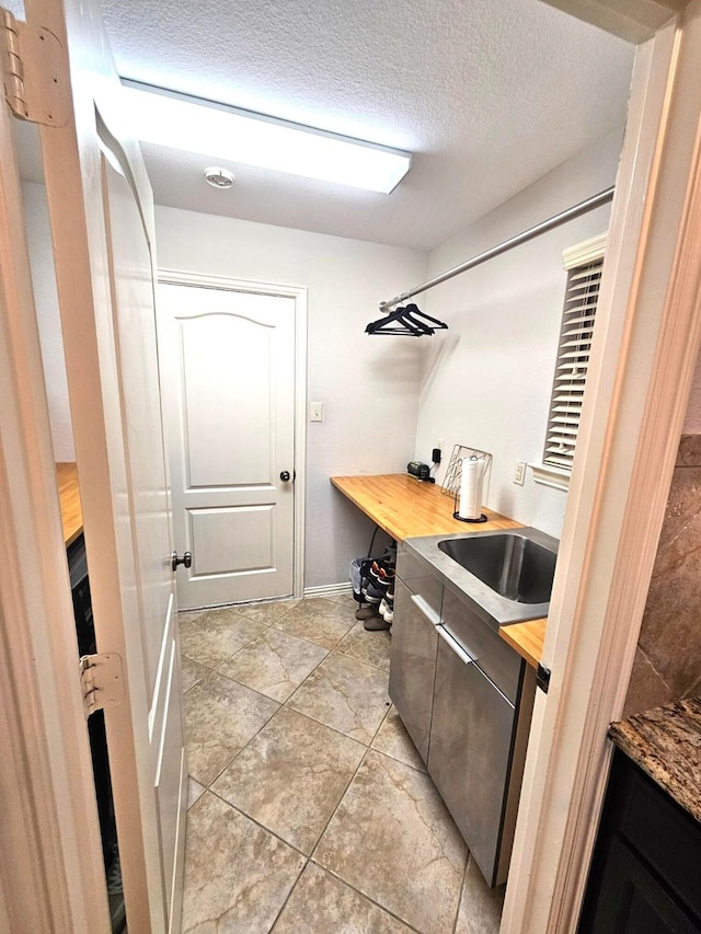 kitchen with a textured ceiling, butcher block countertops, and sink